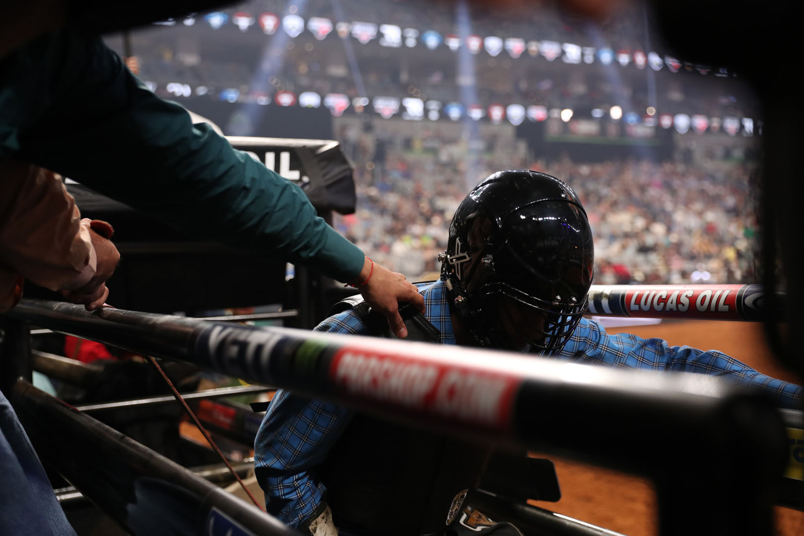 Bull rider and arena crew preparing inside the competition chutes