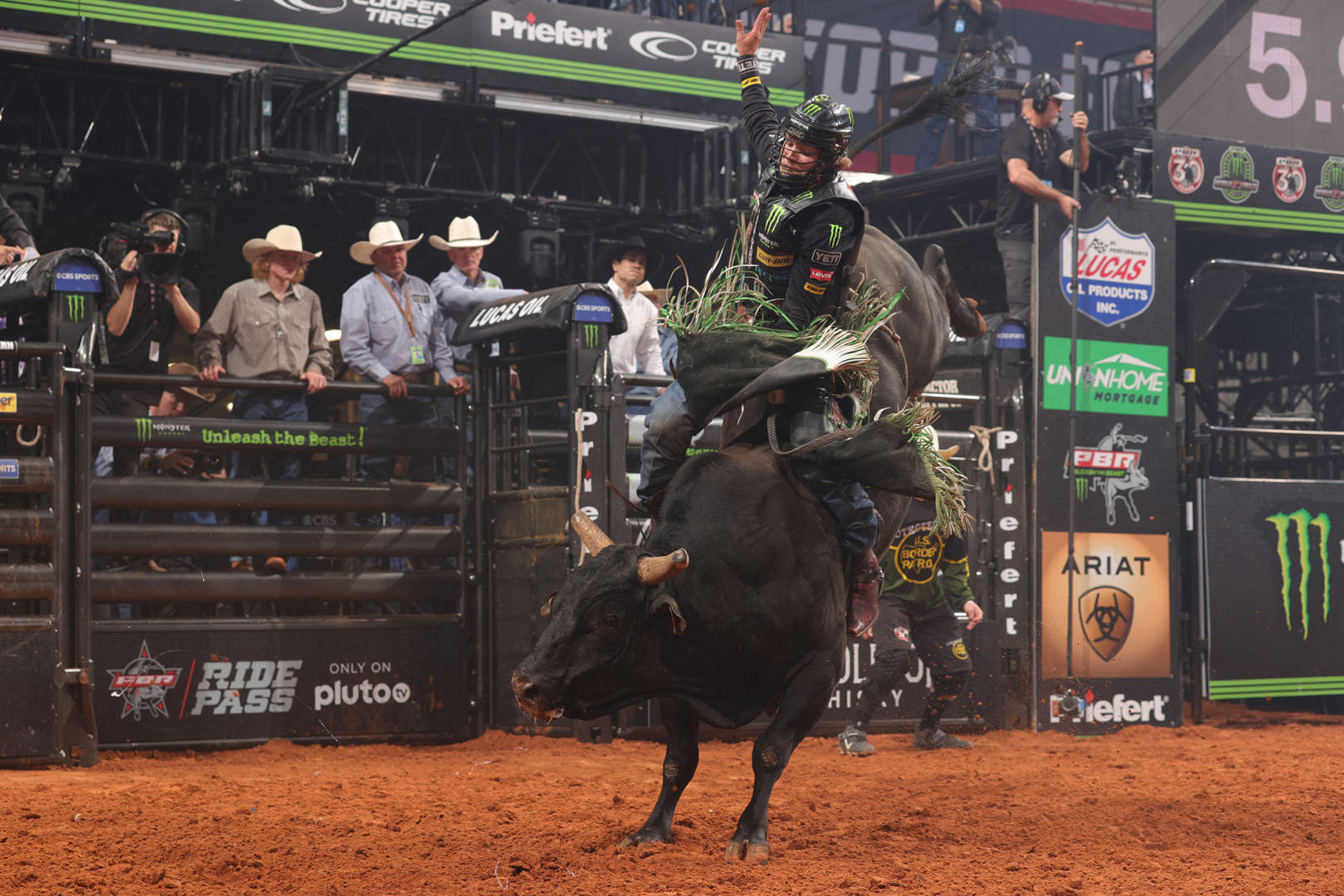 Bull rider in motion as arena officials watch the competition